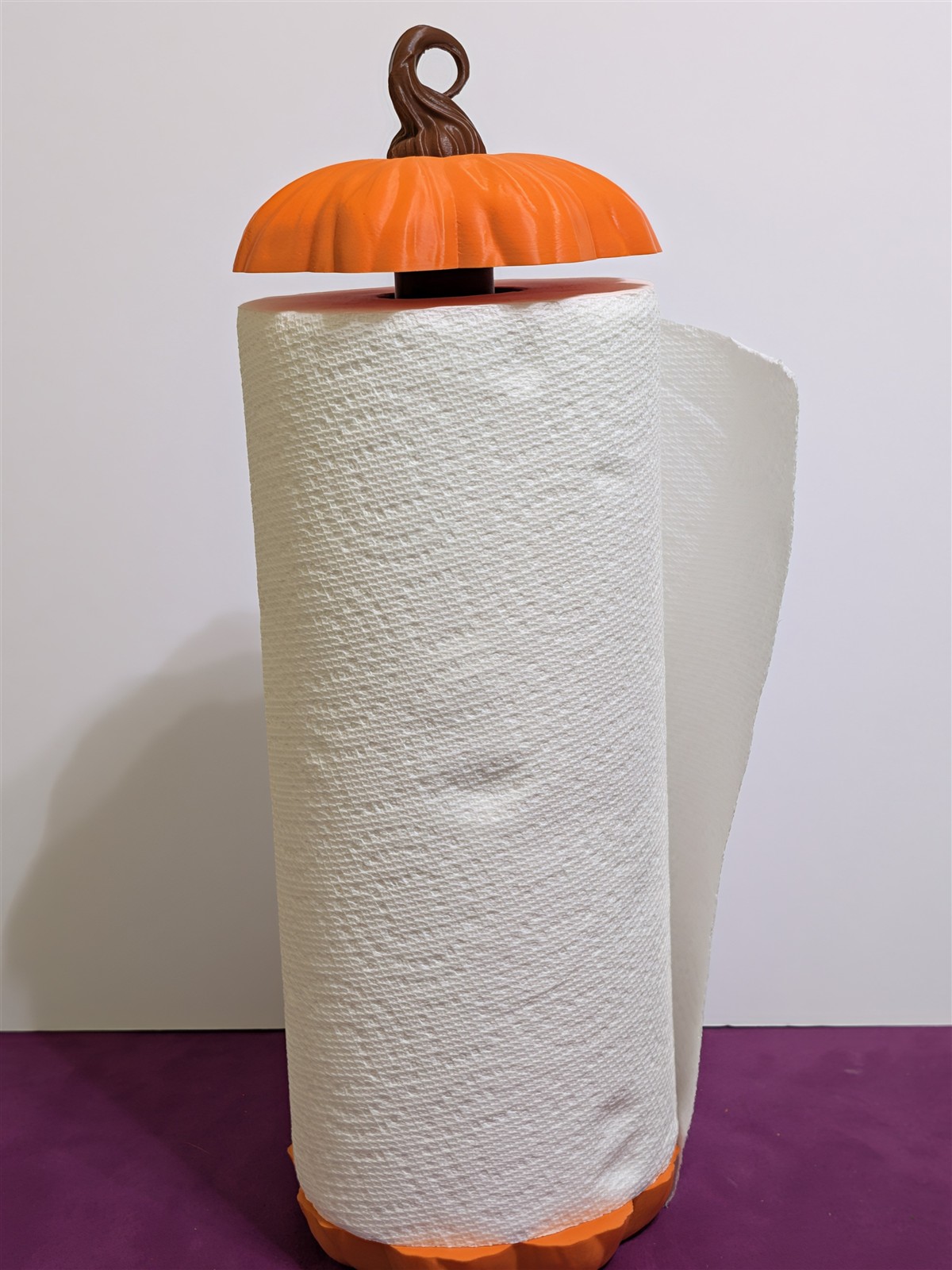 Orange pumpkin paper towel holder with a brown stem and a paper towel roll
